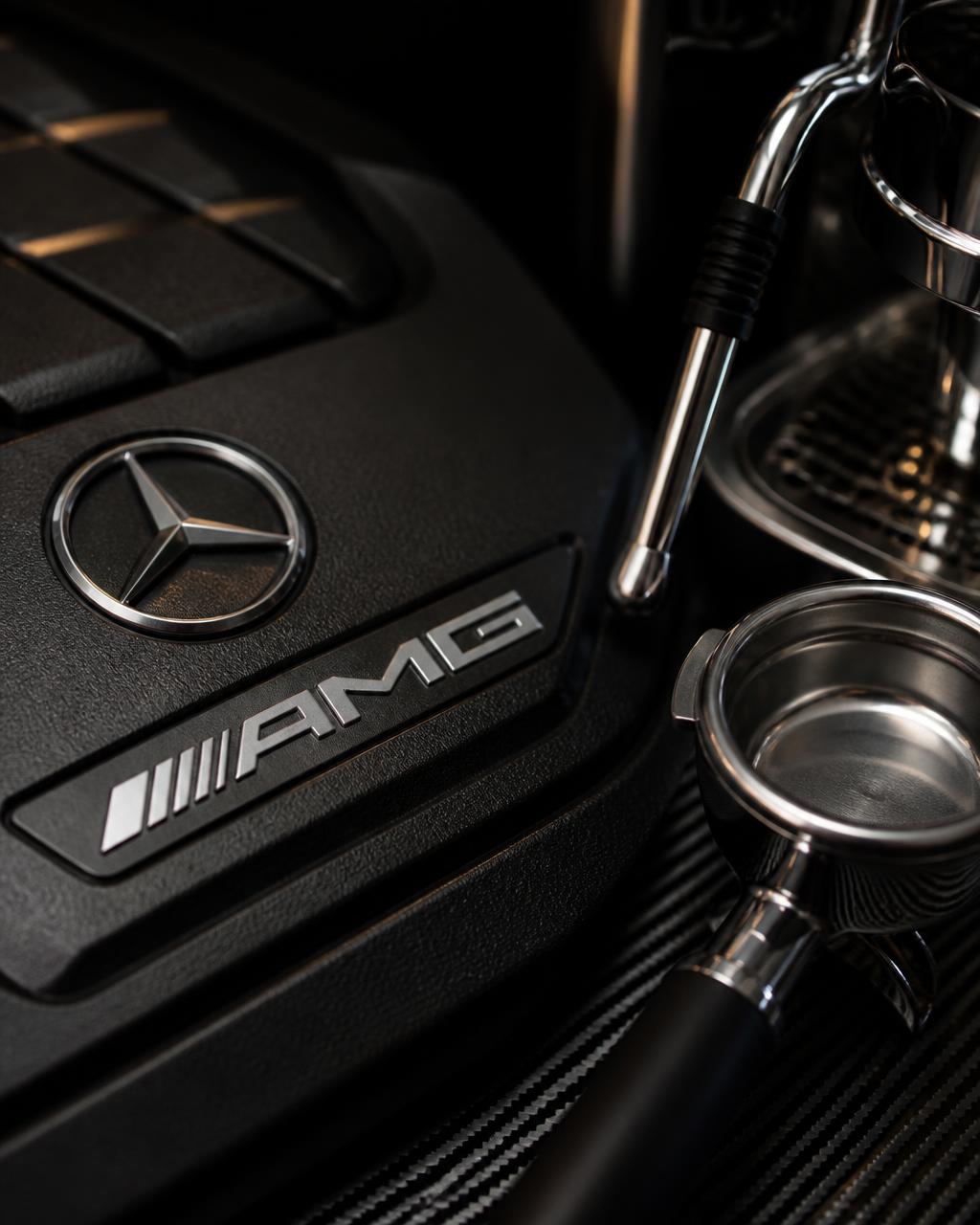 AMG engine badge beside a polished espresso portafilter on carbon fiber